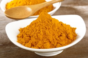 turmeric powder in white dish on wooden